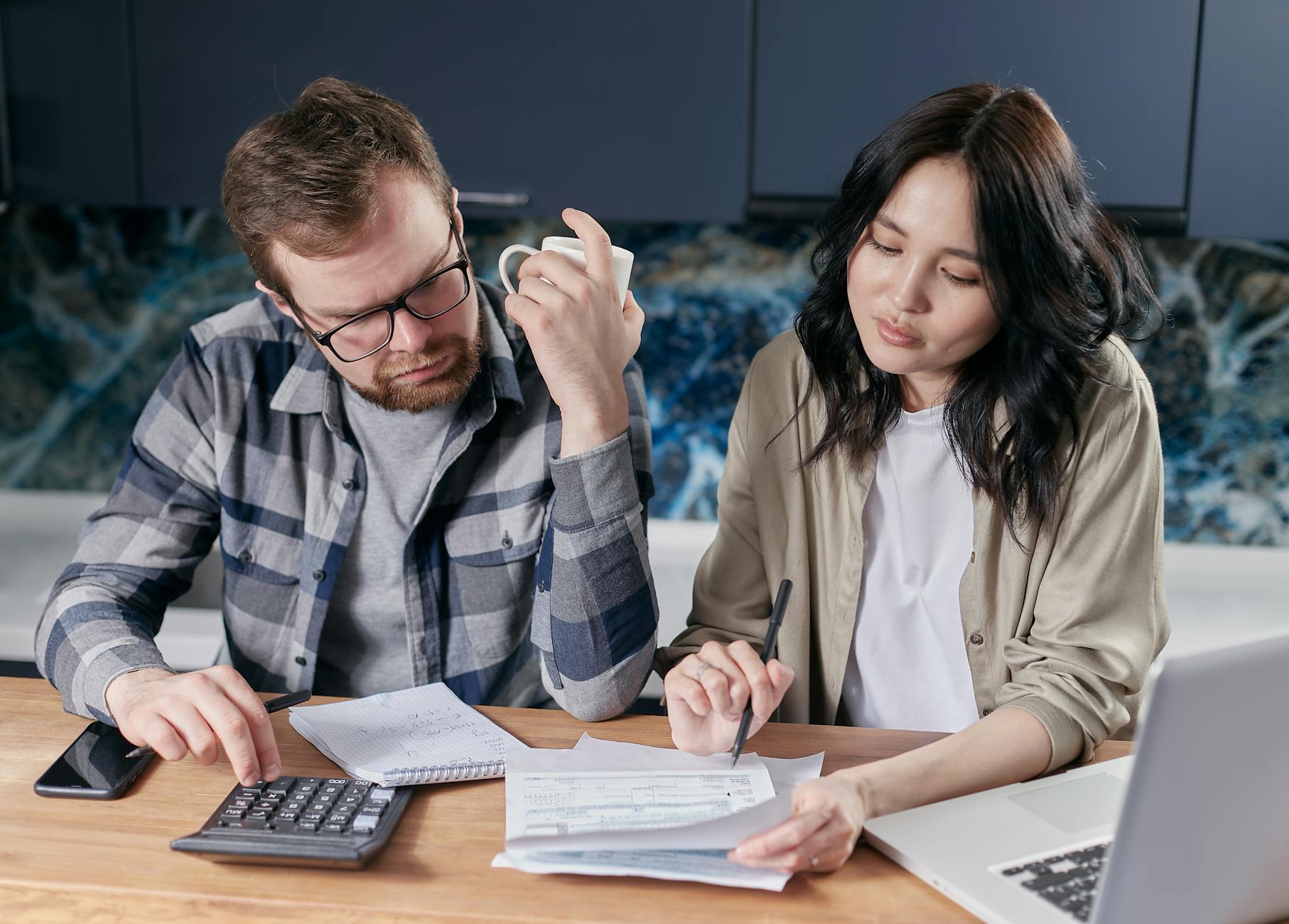 Couple budgeting with a calculator and laptop - smarter financial decisions in Canada