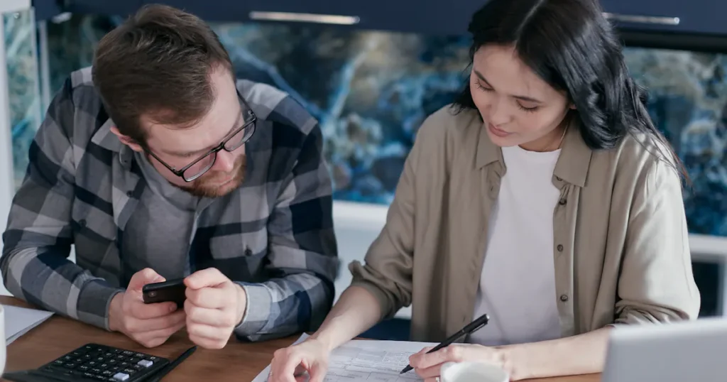A couple at home comparing personal loan options with a calculator and laptop in Canada