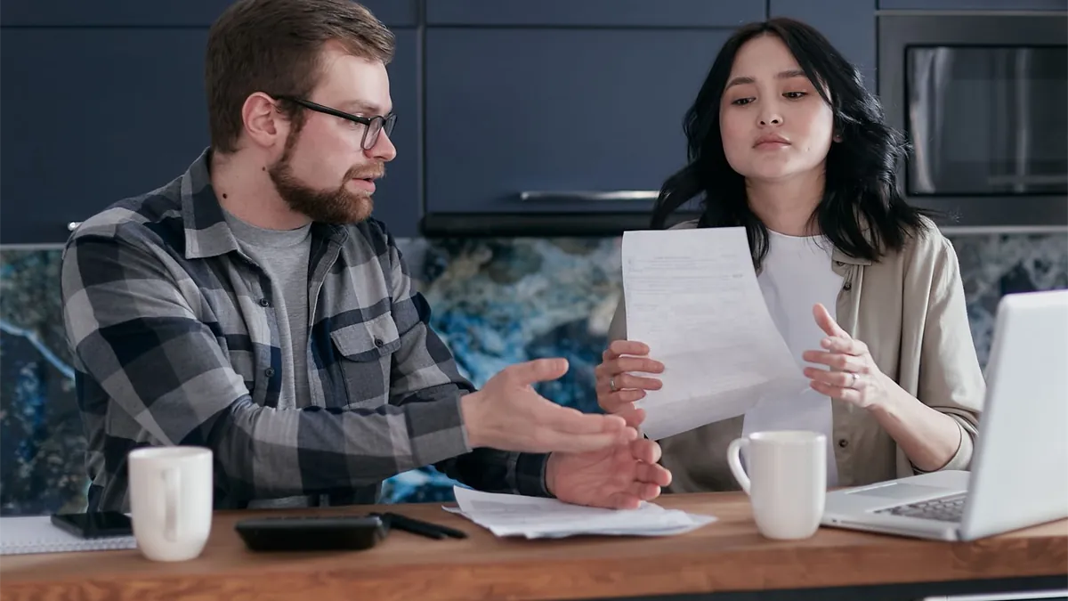 Couple reviewing personal loan rates and documents at their kitchen table