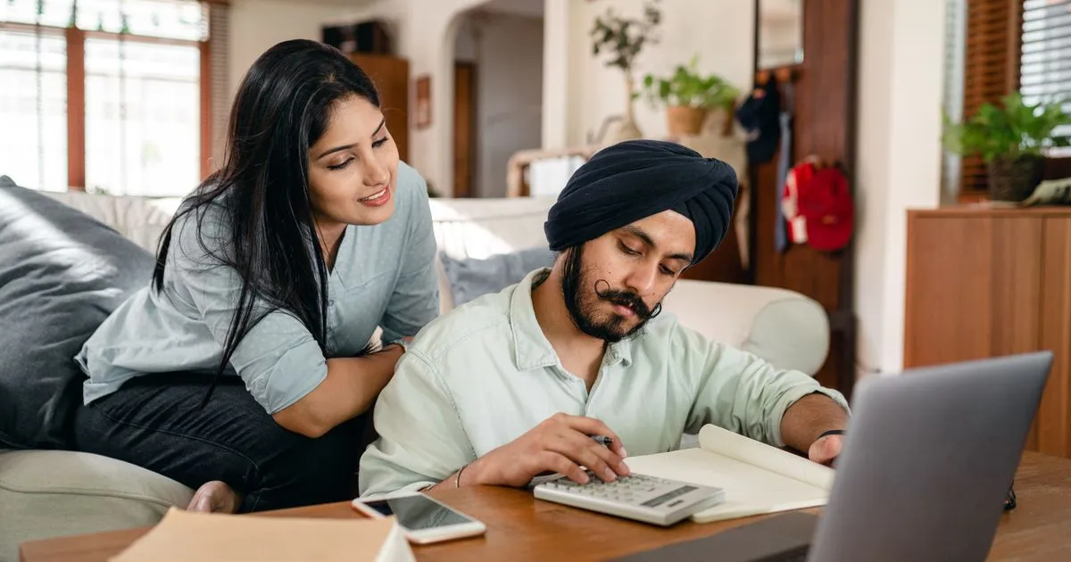Couple comparing 10000 loans in Canada with a calculator and laptop at home