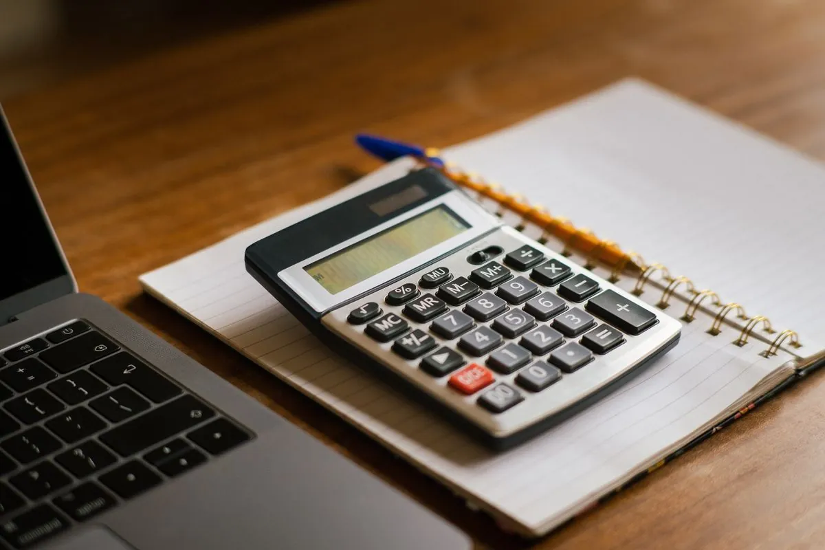 Calculator and notebook working out monthly payments on a $1500 loan