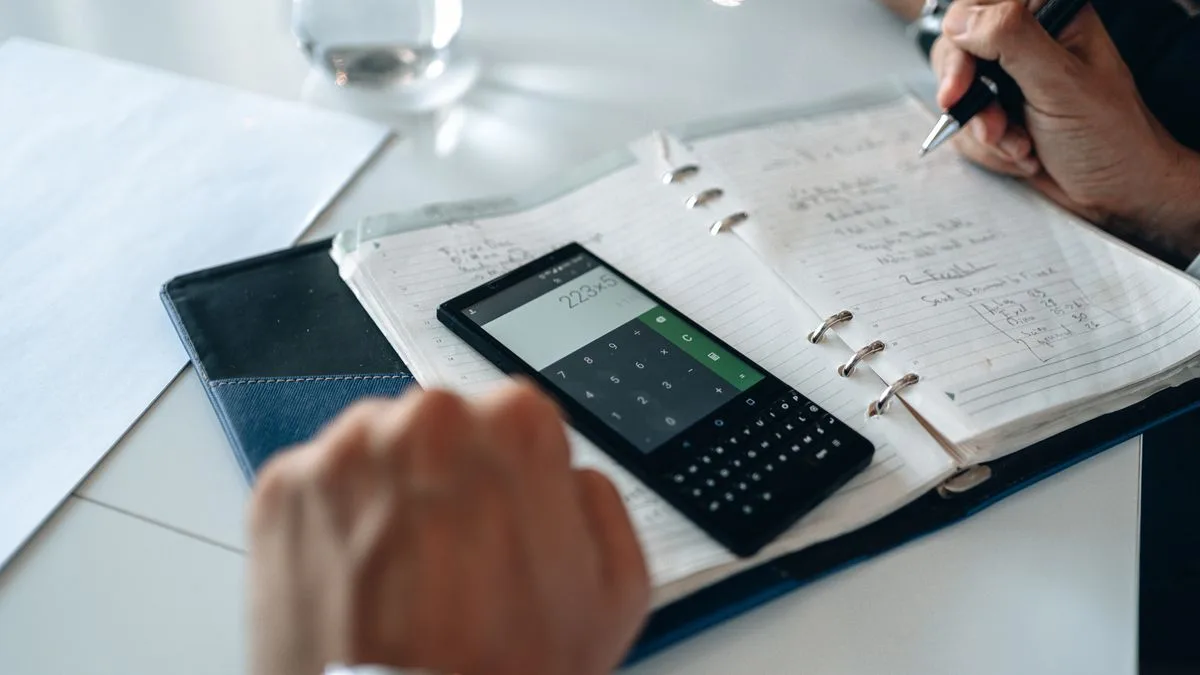 Budgeting the monthly payments on a 750 loan with a calculator and notebook