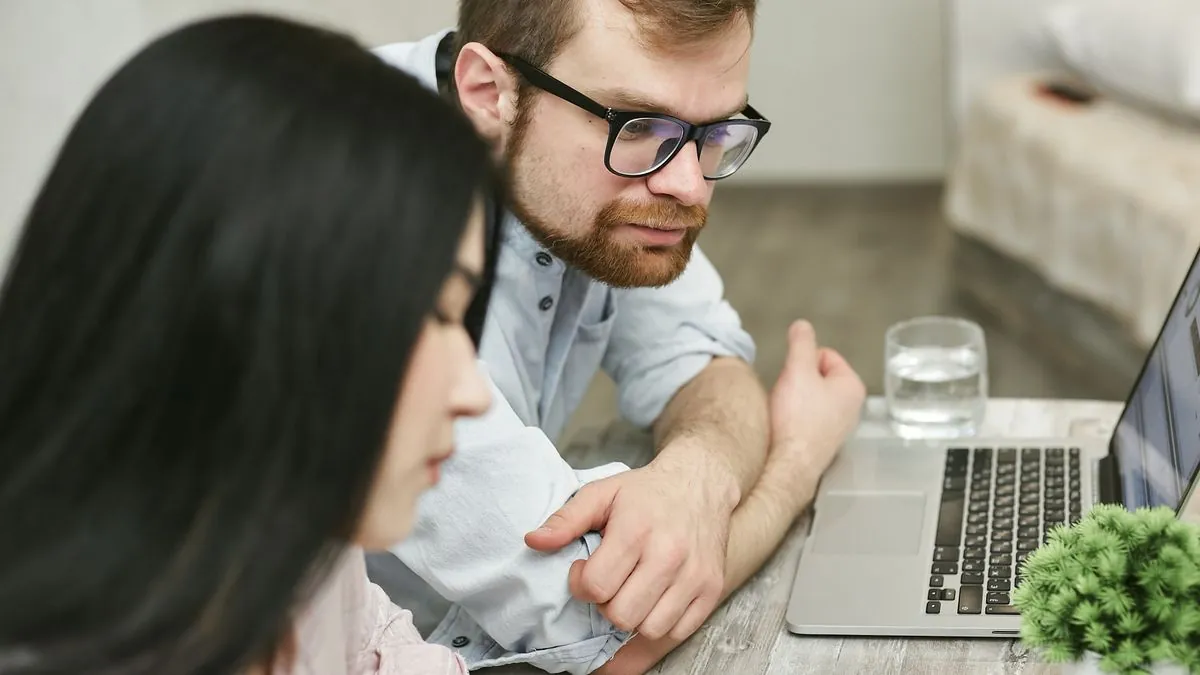 Couple comparing loan offers and interest rates online at home on a laptop
