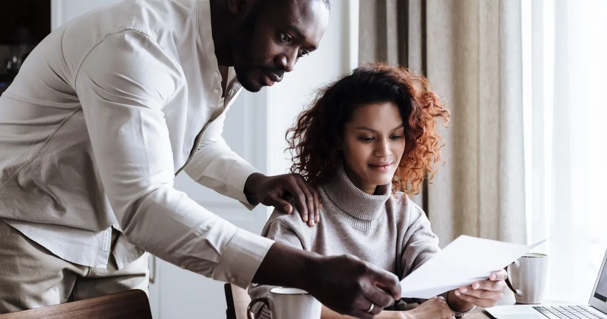Couple comparing 800 loan Canada offers over documents and a laptop at home
