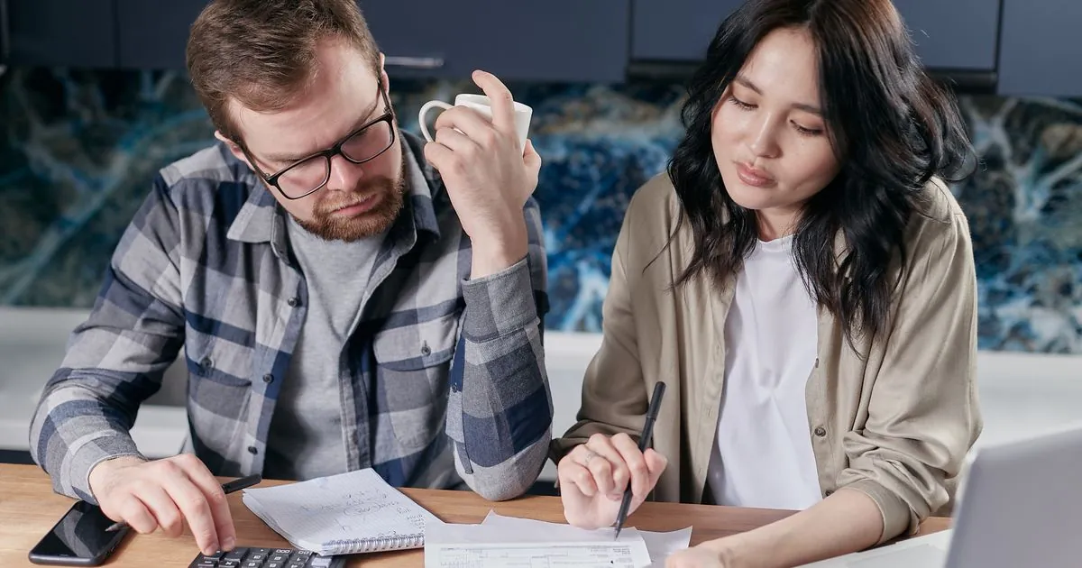 Winnipeg couple comparing installment loan offers with a calculator at their kitchen table