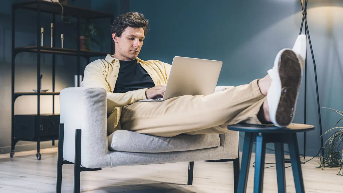 Man in an armchair reading the written cost disclosure on a $2000 loan on his laptop