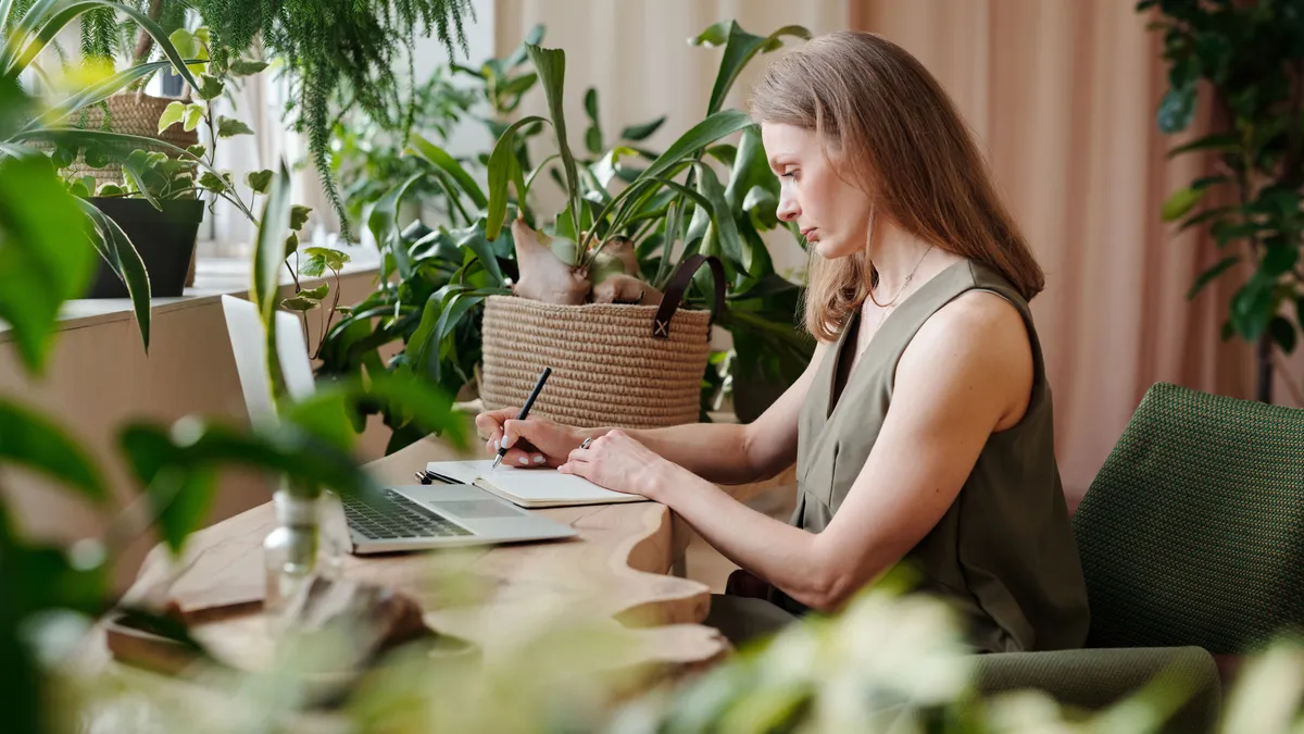 Woman at a desk working out whether a $2000 loan payment fits her monthly take-home pay in a notebook