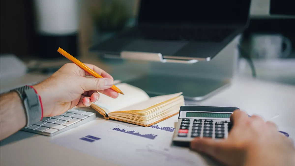 Working out whether a $5000 loan with bad credit payment fits a monthly budget with a calculator and notebook