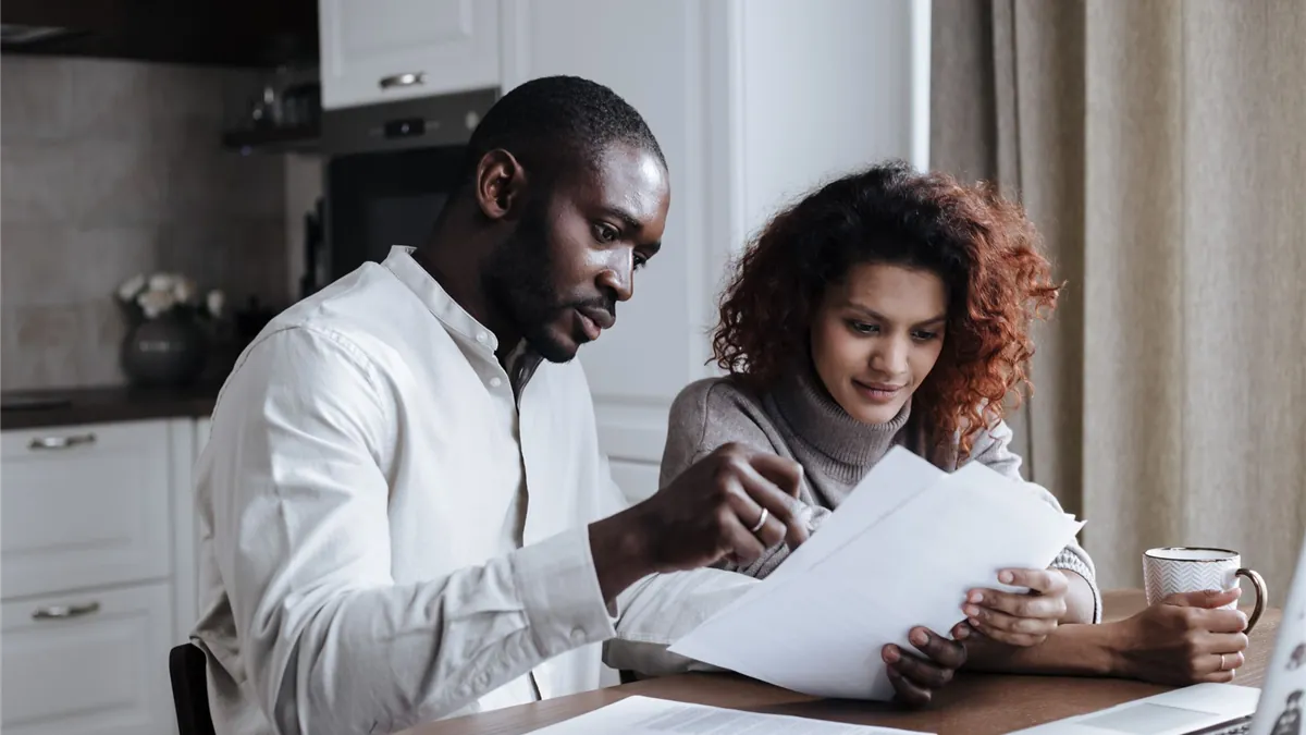 Couple reading a written $5000 loan with bad credit offer together at their kitchen table