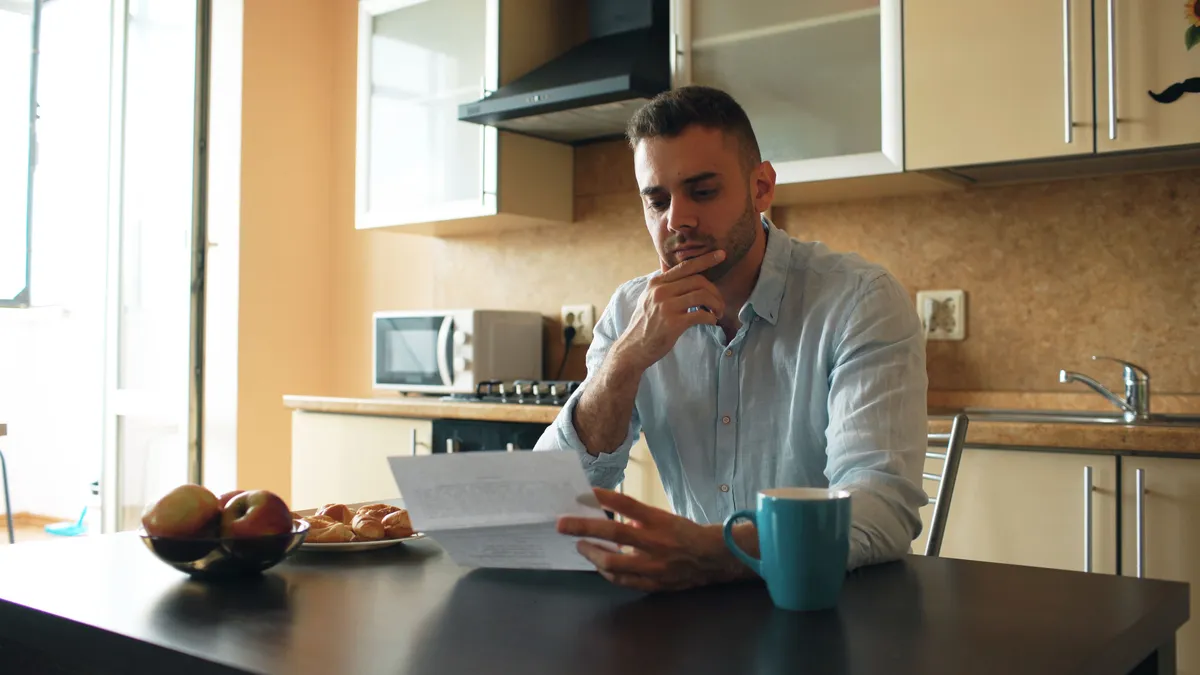 Man in his kitchen reading a letter about bad credit personal loans and his repayment options