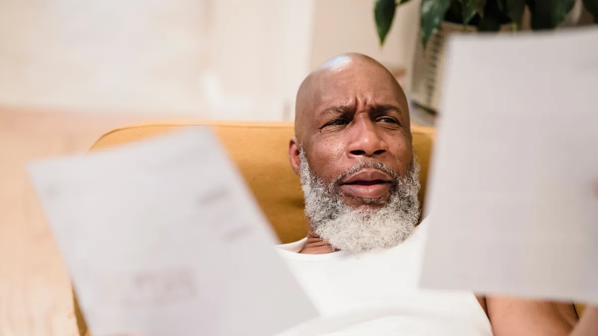 Man reading his loan statements at home, worried about a missed payment on a cosigned loan