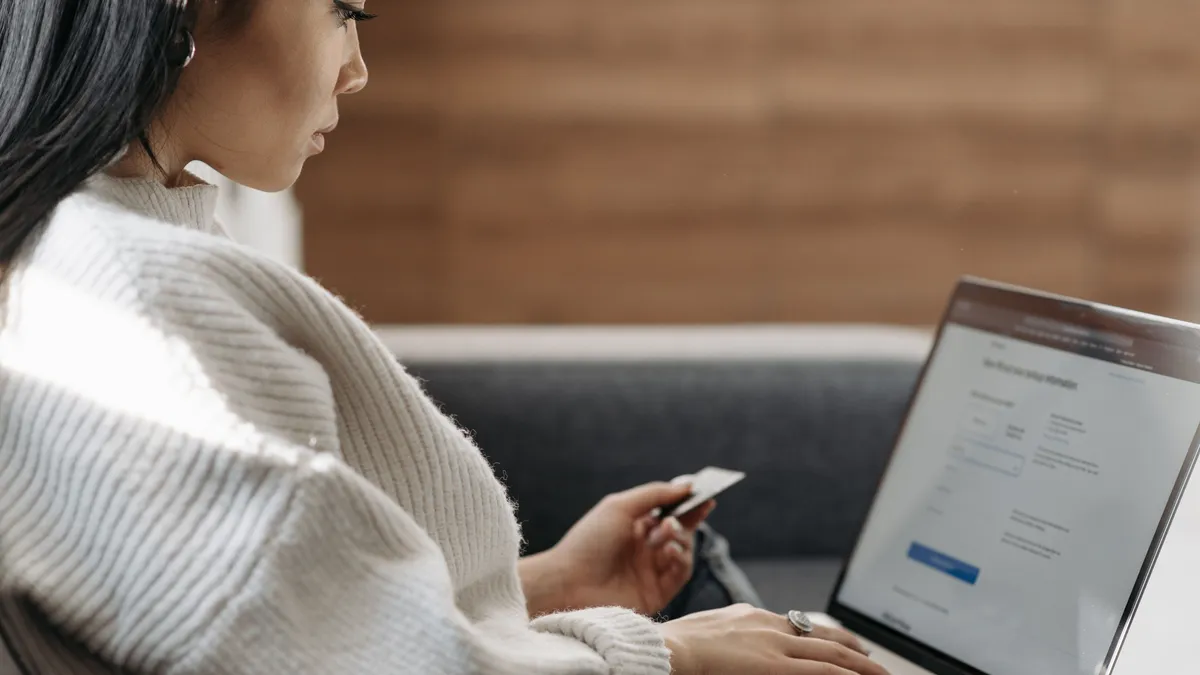 Woman applying for a loan for bad credit online from her couch with a laptop and bank card