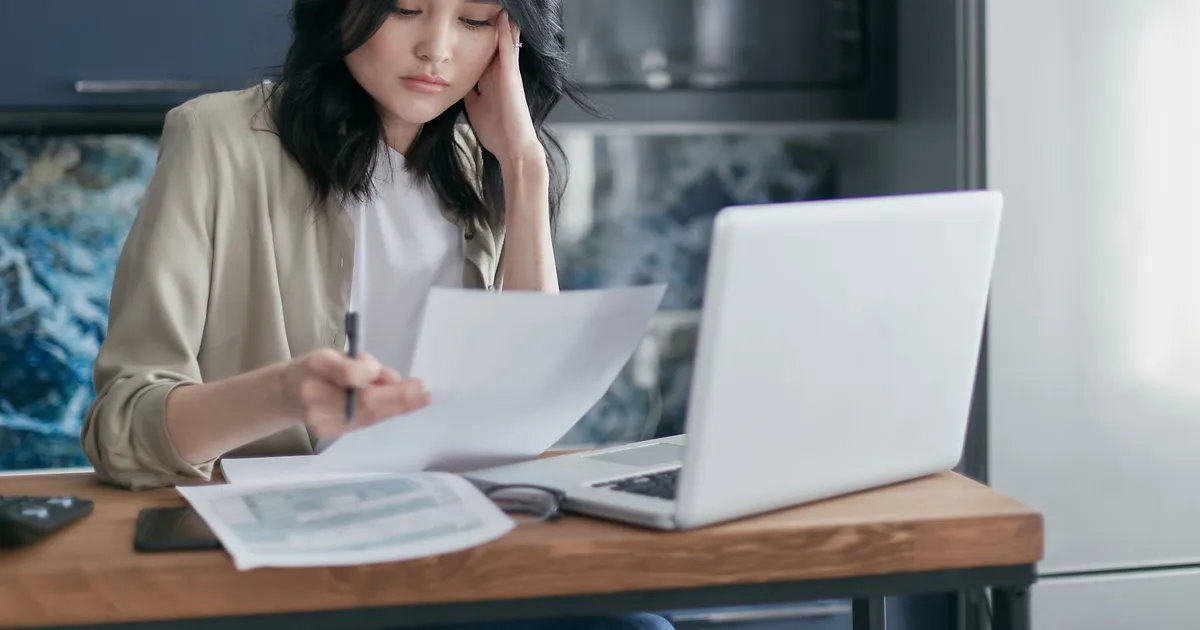 Woman reviewing a loan for bad credit offer and her budget papers beside a laptop at home in Canada