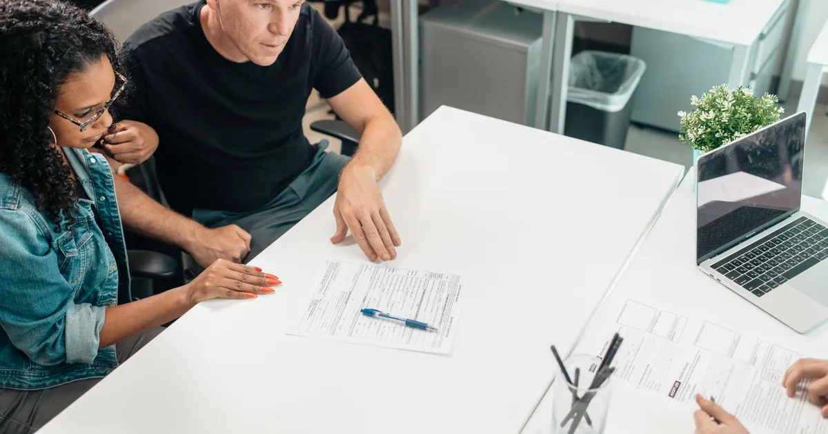 Couple reviewing a personal loan with a cosigner agreement with a lender across a desk in Canada