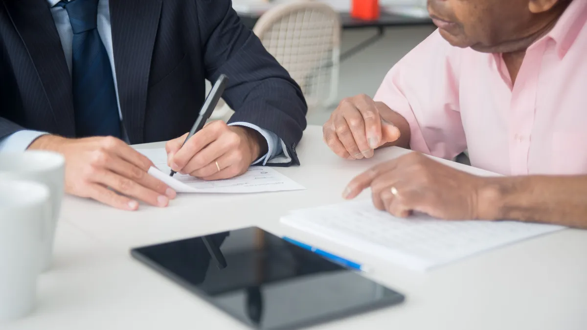 Two people signing personal loan documents at a lender desk
